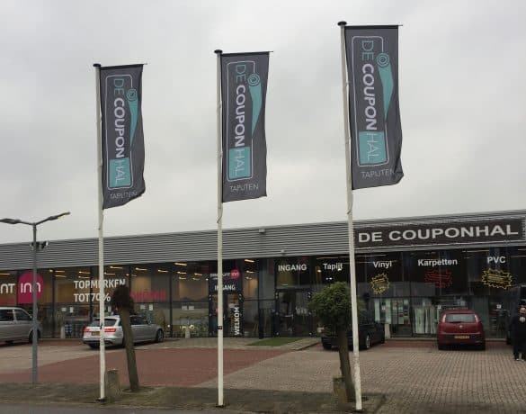 Vlaggen op masten voor de winkel van De Couponhal