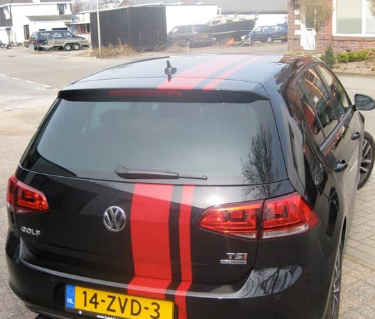 Zwarte Volkswagen Golf met rode rally-striping over dak en achterklep