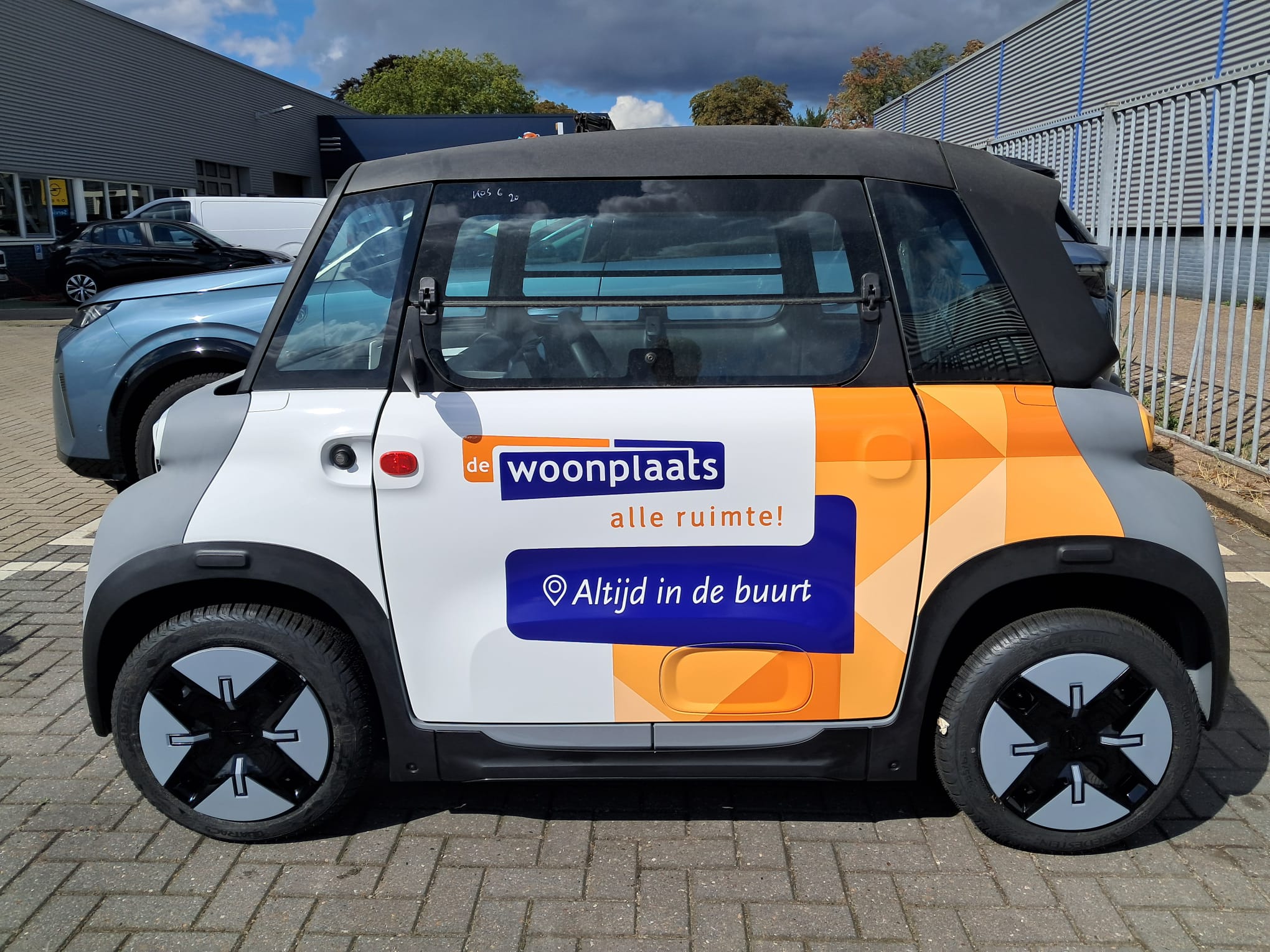 Autoreclame voor De Woonplaats op een compacte elektrische auto